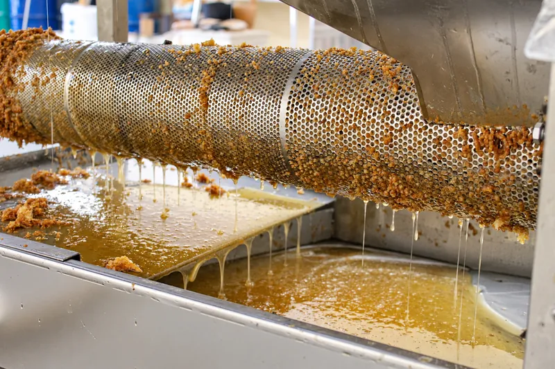 Il cilindro forato dello sceratore, col miele che cola nella vasca